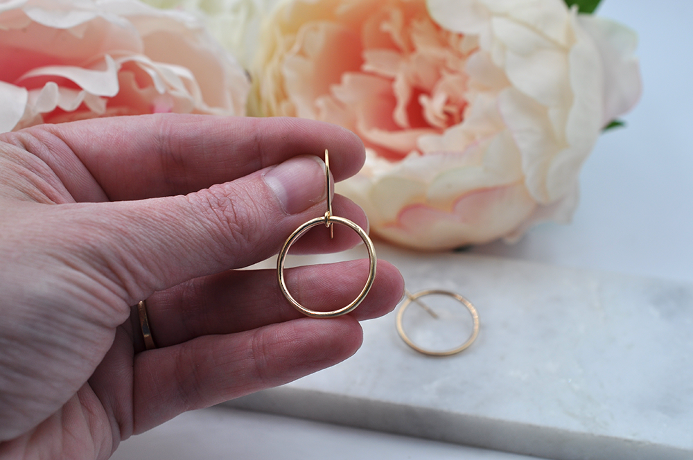 Small gold drop hoop pictured in model's hand for size. Drop hoop width is just shy of one inch. 